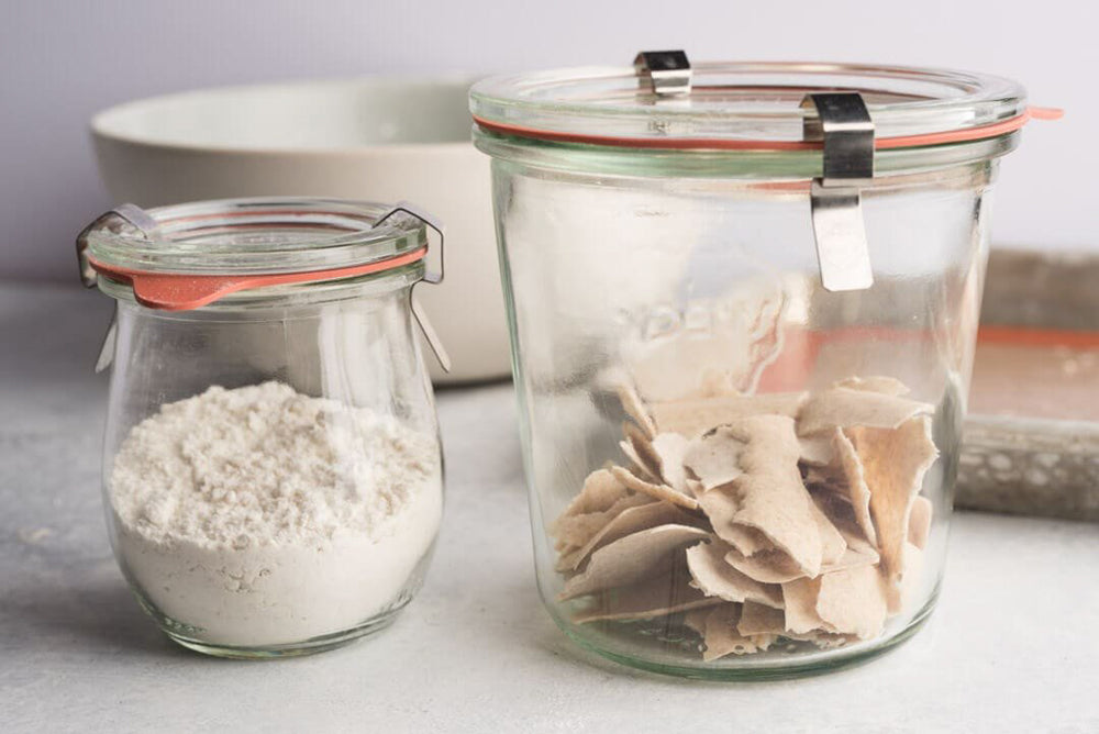 dry sourdough starter sitting on bench with jar or flour