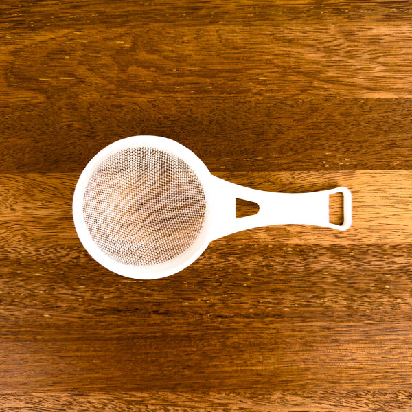 White strainer on a wooden surface
