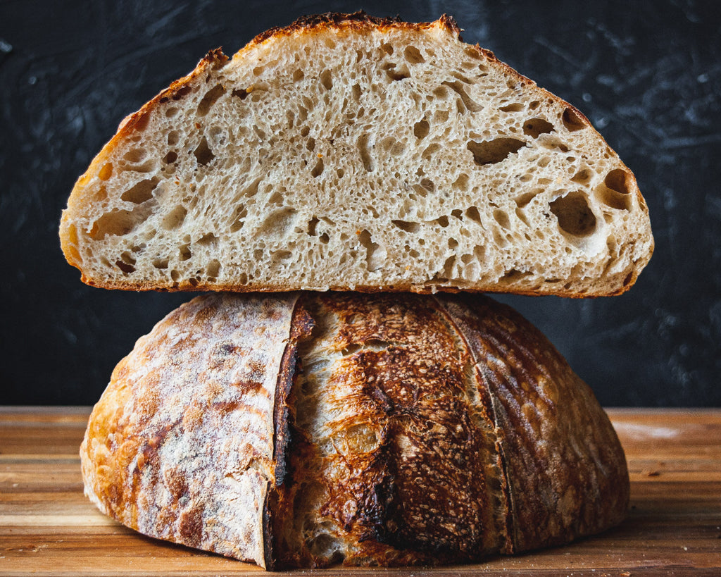 Cut open and stacked sourdough loaf on wooden cutting board.