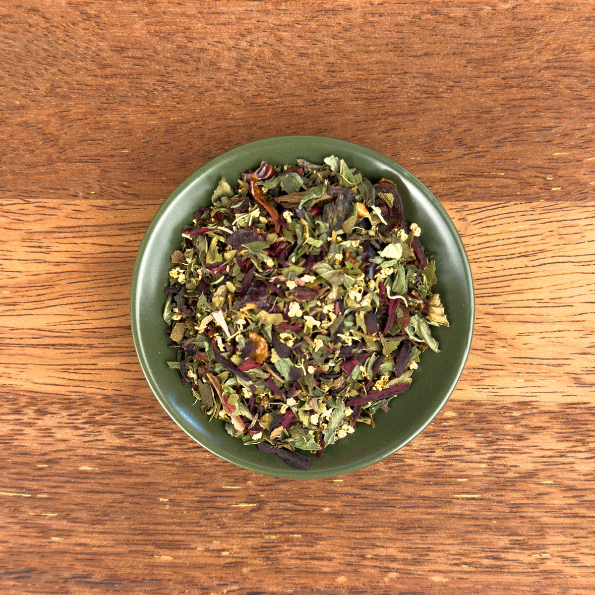 Green bowl filled with dried tea on a wooden surface