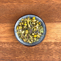 Dried herbs and flowers in a dark blue bowl on a wooden surface