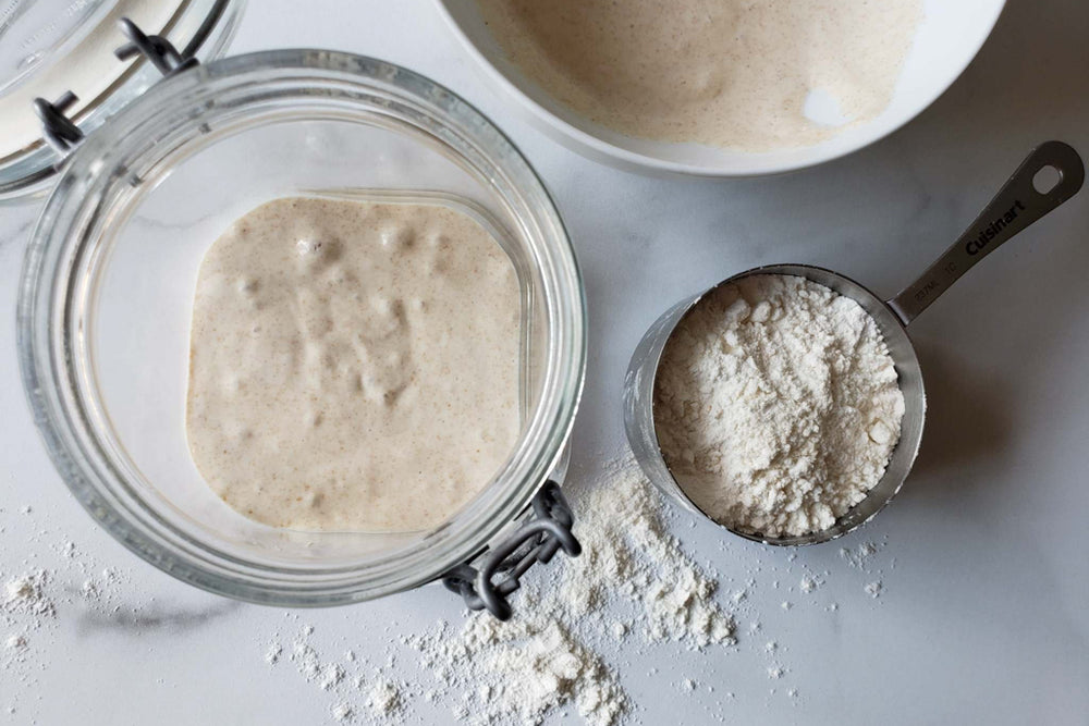 wet sourdough starter in jar and measuring cup of bread flour